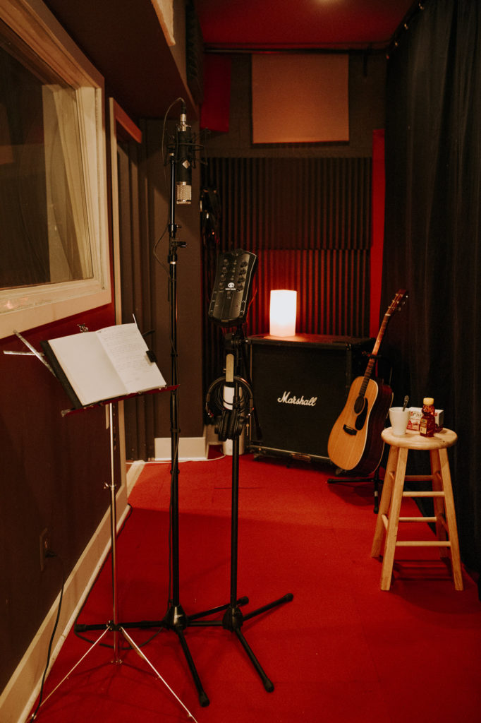 Studio vocal room with a notebook on a stand and a stool